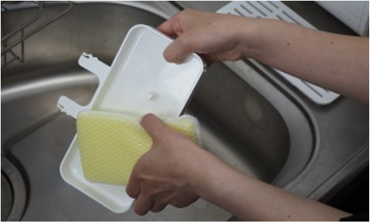 ウォータースタンドの受け皿を洗剤で洗っている女性